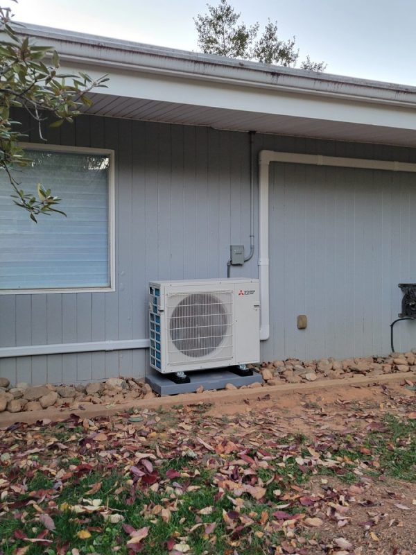 Mitsubishi ductless heat pump outdoor unit beside a ranch-style home in Pikesville, MD